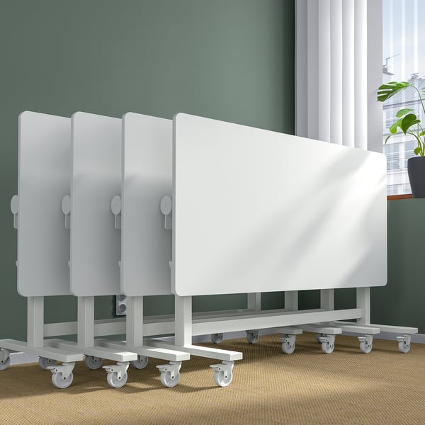 Row of white rollable meeting tables with foldable legs and casters for easy movement and storage.