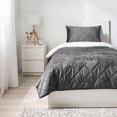 Modern minimalist bedroom with a dark bed and a small nightstand.