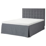 A gray MOSTERHAMN bed with tufted headboard, a white mattress, and a matching skirt, designed for comfortable sleep.