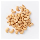 A pile of cashew nuts on a white surface. Key ingredients: cashews. Texture: crunchy.