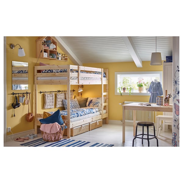 Childs bedroom with MYDAL bunk beds, yellow walls, blue-white bedding, wooden desk & stool, striped rug, wall mirror, and various decorations.
