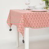 Red tablecloth with white floral pattern secured with black clips on a dining table, ready for a meal.