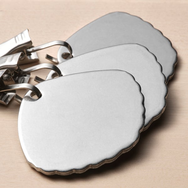 Three stainless steel tablecloth clips secure outdoors.