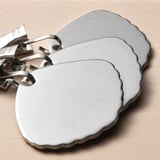 Three stainless steel tablecloth clips secure outdoors.