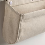 Close-up of beige fabric bag with stitched edges and a press stud, showcasing its sturdy craftsmanship.