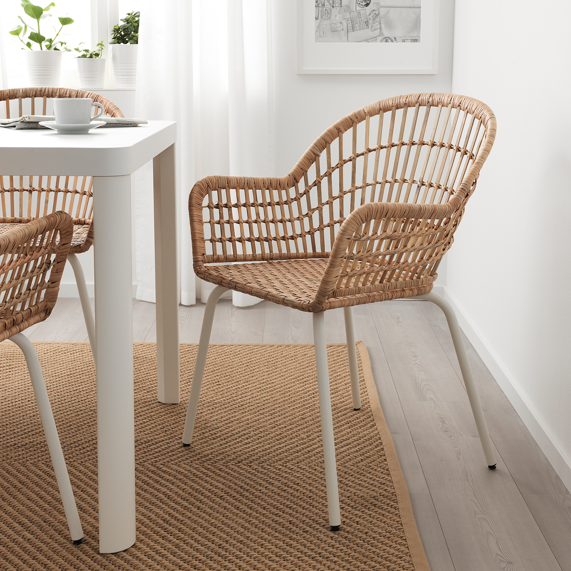 Two NILSOVE rattan armchairs with white metal legs under dining table, minimalist setting.