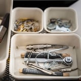 Organized drawer with NOJIG white plastic boxes containing various metal tools and watch parts, neatly arranged, suitable for hardware or watchmaking.