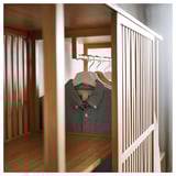 Scandinavian-style NORDKISA wardrobe in bamboo. Gray shirt hangs on a sliding door, dividing sides with open shelves.