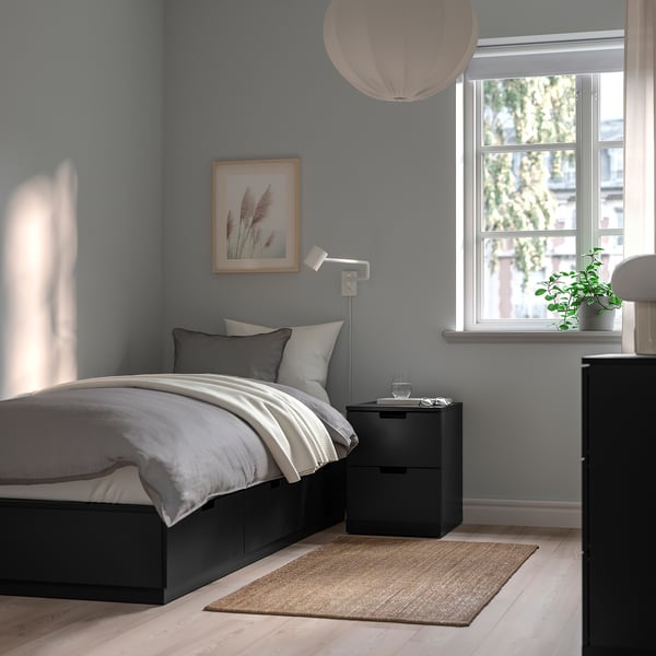 Modern bedroom with NORDLI bed, pendant lamp, plant, and efficient storage.