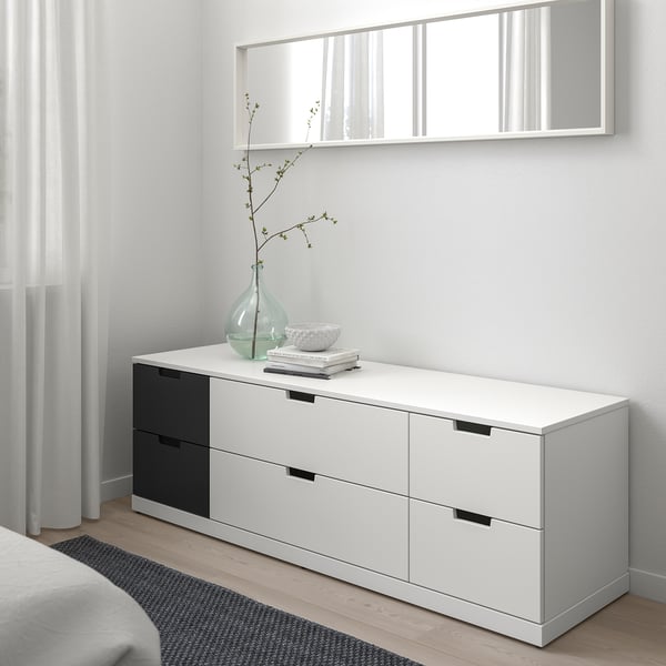 Modern NORDLI chest: 6 drawers, half black/white, with vase & books below mirror.