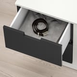 Open NORDLI drawer revealing a black belt and grey shirt, demonstrating its storage capacity.