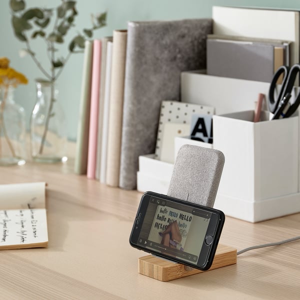 Wireless charging stand with phone displaying hello on home office desk.