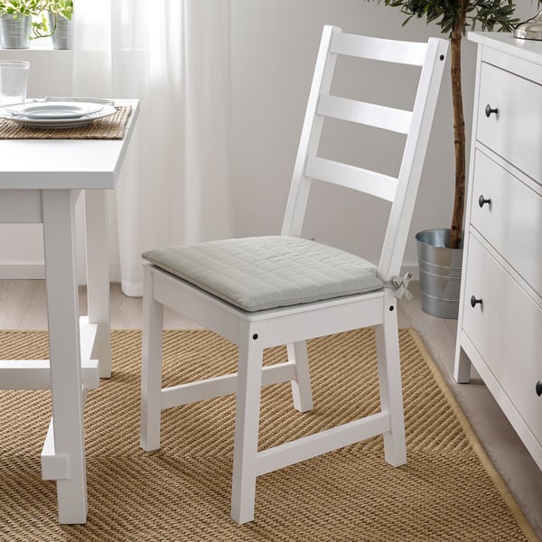 White NORDVIKEN chair with cushion next to matching table and dresser in bright room.
