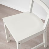 White wooden chair with a high back on a light wooden floor. The chair has a deep seat and a smooth, finished surface.