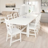 Bright dining room with white NORDVIKEN extendable table seating 8. Matching white chairs, big window, natural light, adjacent living space with sofa.