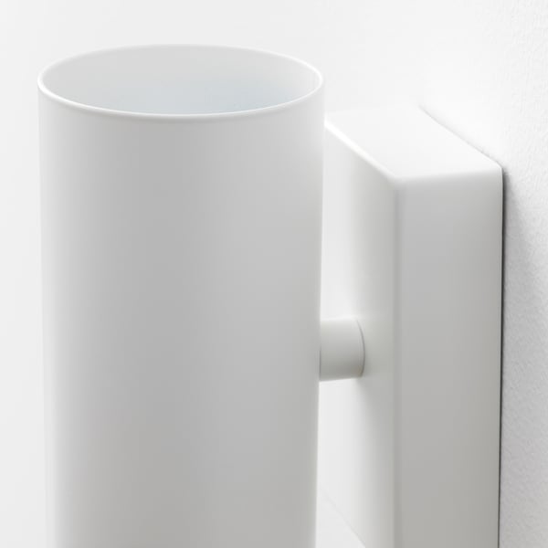 Modern white wall-mounted light fixture with rounded shade and sturdy base, emitting downward light.