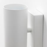 Modern white wall-mounted light fixture with rounded shade and sturdy base, emitting downward light.