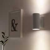 Wall-mounted light fixture with downward glow and upward light reflection.