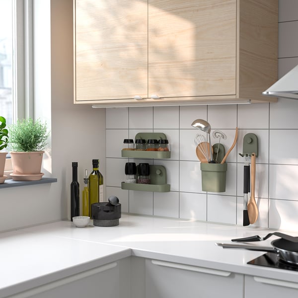 Modern kitchen with wooden cabinets and white tiles. Green ÖBONÄS wall organizers hold kitchen items.