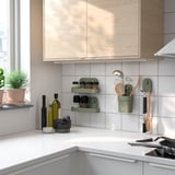 Modern kitchen with wooden cabinets and white tiles. Green ÖBONÄS wall organizers hold kitchen items.