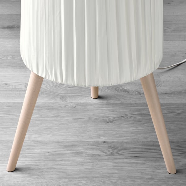 Modern floor lamp with pleated white shade and wooden legs.
