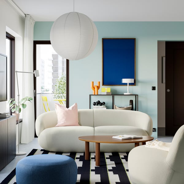 Modern living room with blue walls, white sofa, wooden coffee table, hanging lamp, and blue artwork.