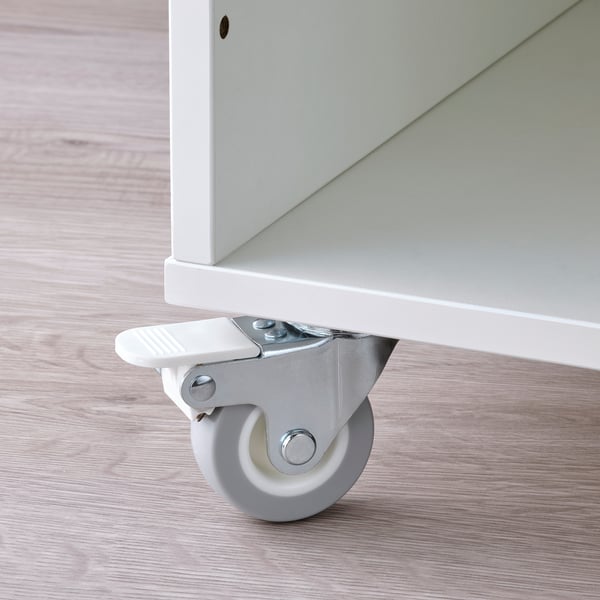 Close-up of a white caster wheel attached to a white wooden furniture leg on a light wooden floor.
