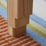 Wooden bench with intricate, woven textile sides, showcasing high-quality craftsmanship and natural materials.