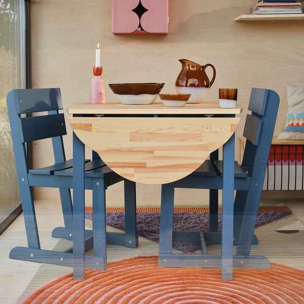 OMMJÄNGE blue pine table with foldable leaves, small, with bowls and pitcher, colorful rug.