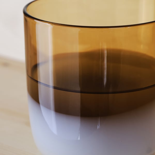 Amber glass bottle, mouth-blown with smooth edges, sitting on a wooden surface, showcasing its high-quality craftsmanship.