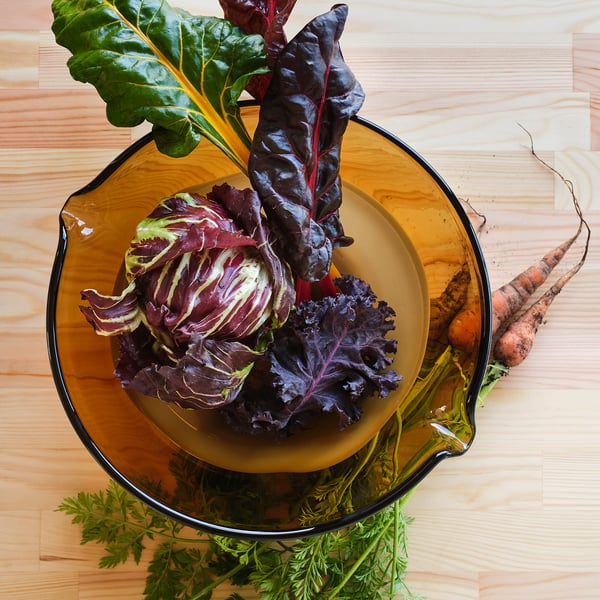 Glass bowl with colorful vegetables on wooden table.