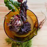 Glass bowl with colorful vegetables on wooden table.