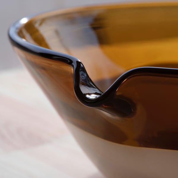 Amber-colored glass bowl with smooth, reflective surface and elegant, curved handle.