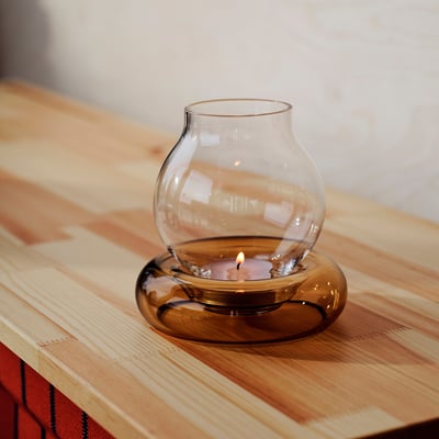 Glass dome candle holder with brown base, warm candlelight, fits in one hand, rustic charm.