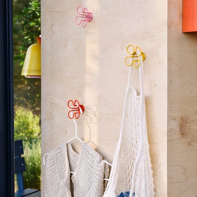 Colorful floral wall hooks hold crocheted garment & netted bag.