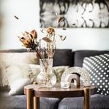 Living room with PÅDRAG vase, dried flowers, rainbow decor, candle, and sofa with pillows.