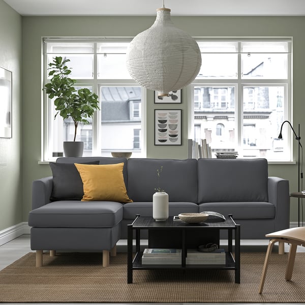 Modern living room with grey PÄRUP sofa, pillow, coffee table, pendant light, and urban view.