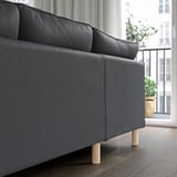 Modern, gray sofa with wooden legs, near window and plant. Comfortable and easy to clean with removable, washable cover.