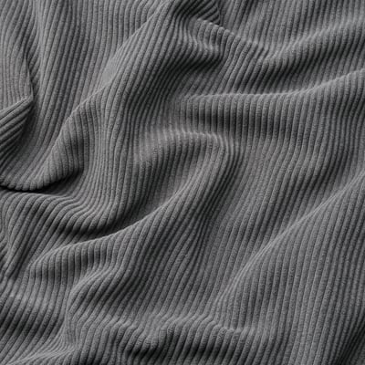 Close-up of thick, textured corduroy fabric with visible wavy lines, showcasing its soft and comfortable quality.