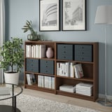 Wooden PALLRA storage unit with grey drawers against blue walls, holding books and decor. Lamp, plant, and photos nearby.