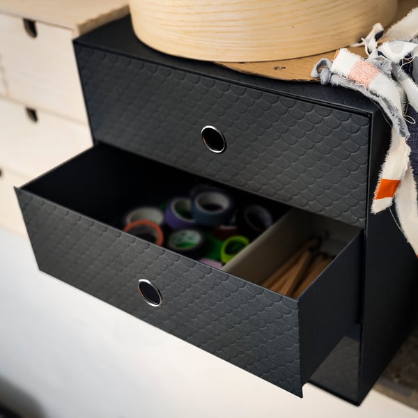 Black PALLRA storage box, open showing colorful items, black textured exterior, metal handles.