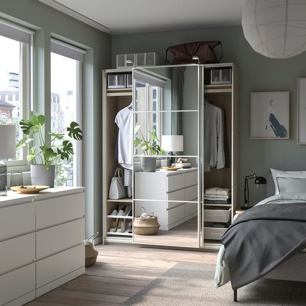 Bedroom with PAX wardrobe, white. Drawers, shelves, and hanging space. Decorated with plants and artwork.
