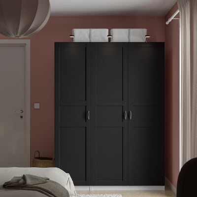 Black PAX wardrobe, closed, against red wall, with basket, dominates room.