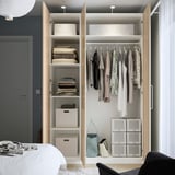 Wooden wardrobe with open doors revealing neatly organized clothes and storage.