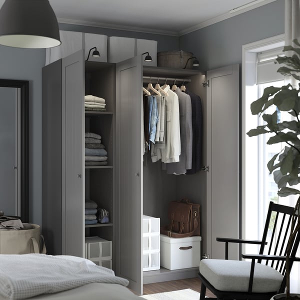 A modern gray wardrobe with open doors revealing clothes and shelves, integrated lighting, and a hanging rod, demonstrating organized storage space.