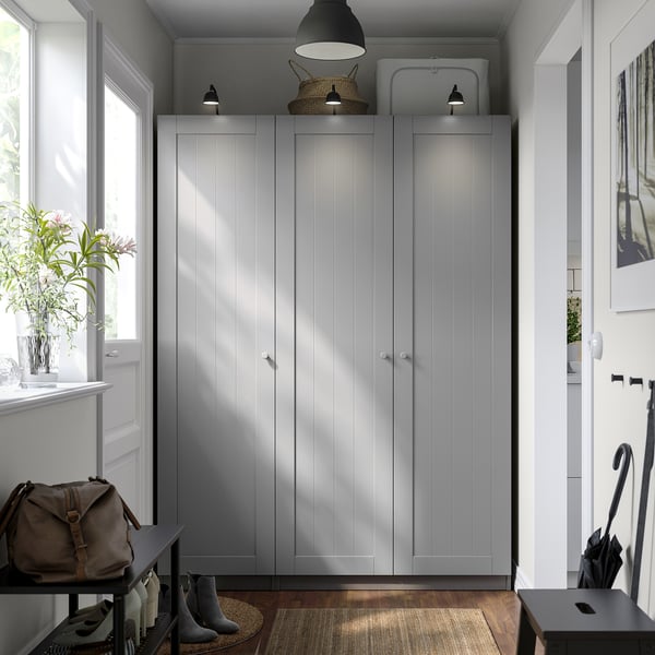 Minimalist entryway with light gray PAX wardrobe, white door, and small table with hooks.