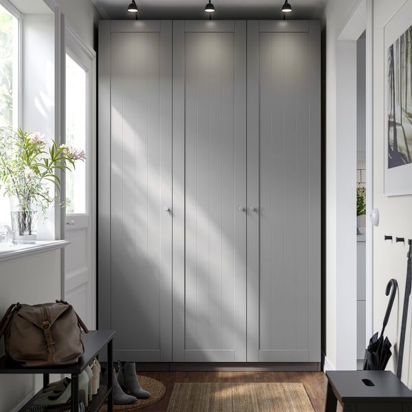 Modern entryway with large gray PAX closet, black shoe rack, brown bag, plant, and umbrella stand.