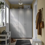 Modern entryway with gray PAX wardrobes, white bench, hanging coats, and window plant.