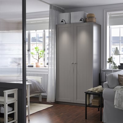 Modern gray PAX wardrobe, corner-fit, smooth panels, taller than sofa/chair.