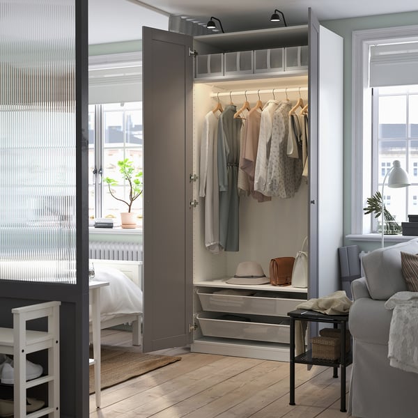 Closed wardrobe with clothes, hats, and bags, beside an open wardrobe.